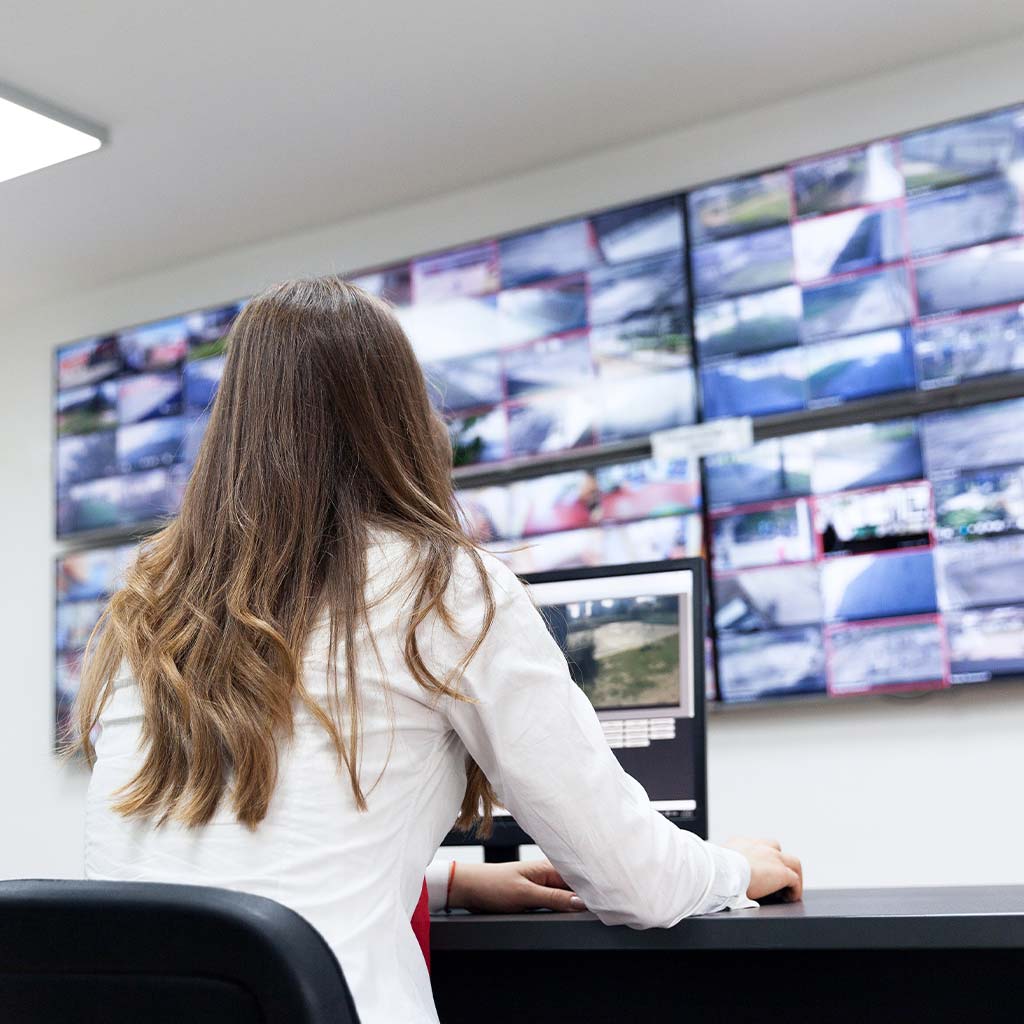 operator sitting in control room monitoring security camera displays on video wall