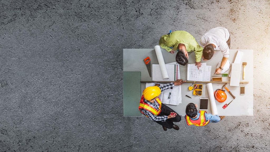 design team working on table in open control room, aerial view