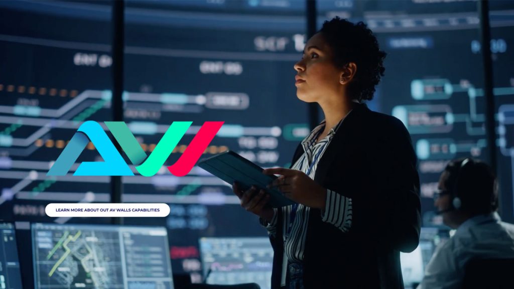 security operator standing in front of av video wall in dark control room